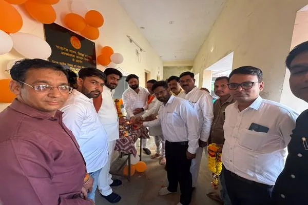 छात्रावास के बरामदे में खड़े लोग, दीवार पर काले पत्थर की शिलालेख पट्टिका, नारंगी और सफेद गुब्बारे तथा गेंदे की माला से सजा प्रवेश द्वार।